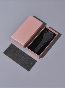 Pink rectangular watch box detail showing paper texture and black foam lining insert