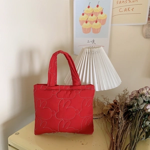 Detail of red quilted bunny handbag showing white stitched rabbit patterns and soft texture
