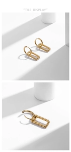 Macro shot of gold-plated titanium earrings with twisted texture and rectangular drop details