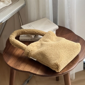 Close-up of yellow teddy fleece handbag with Simple Wish label on wooden bench