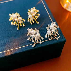 Close-up of gold and silver plated pearl earrings with zircon in a premium jewelry box
