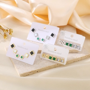 Close-up of minimalist square and rhombus stainless steel studs with zircon on silk