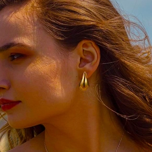 Close-up of model wearing 18k gold plated hollow teardrop earrings in sunlight