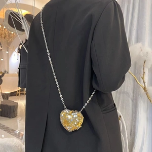Detail shot of heart shaped evening bag with gold sequins and silver metal chain strap