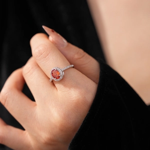 Detailed macro view of an elegant orange oval gemstone ring with a halo of zircon stones