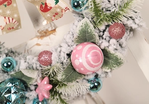 Close-up of flocking PVC Christmas wreath with pink blue ornaments and burlap ribbon