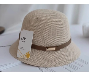 Dettaglio cappello di paglia beige con cinturino in pelle marrone e fibbia oro