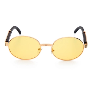 Detalle de gafas de sol ovaladas con lentes amarillas y montura fina de metal dorado