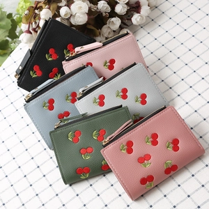 Detailed close-up of cherry embroidered wallets in multiple colors with gold zippers