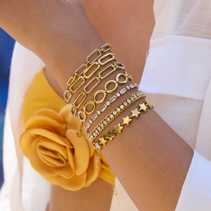 Detail of layered gold star bracelets with zircon inlay worn by a model in soft light