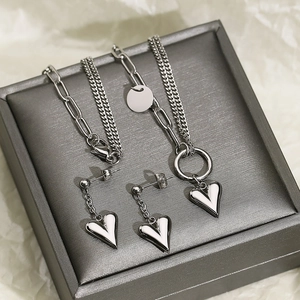 Detailed view of silver heart jewelry set with layered necklace and matching drop earrings