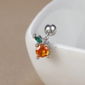 Macro shot of silver barbell stud with orange zircon and green leaf on white cup
