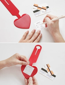 Detail showing red heart luggage tag with info card and cross-grain leather texture