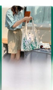 Detailed view of canvas tote bag featuring chamomile floral print and Don't ever change text
