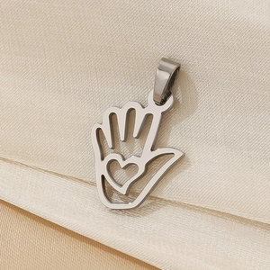 Macro shot of silver palm pendant with hollow heart detail on champagne fabric