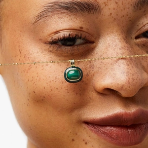 Close-up of gold plated necklace featuring a natural green malachite square pendant on skin