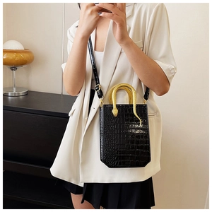 Detail of black faux leather tote with creative gold snake handle worn by model