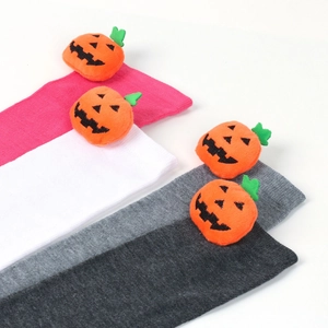 Detail of plush orange pumpkin ornaments on striped Halloween over-knee socks