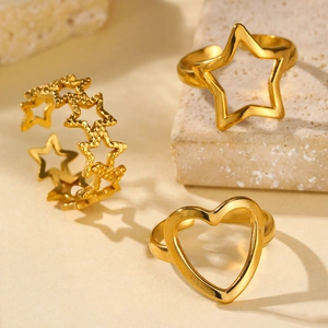 Detail of 18k gold-plated stainless steel star and heart shaped rings on stone surface