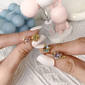 Close-up of star and planet earrings with colorful zircons held by hand