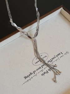 Detail of silver multi-layer twisted snake chain necklace with hanging bead charms