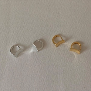 Close-up of curved brushed rectangular studs in gold and silver finish on white paper