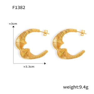 Détail des boucles d'oreilles dorées irrégulières en forme de C avec fils enroulés