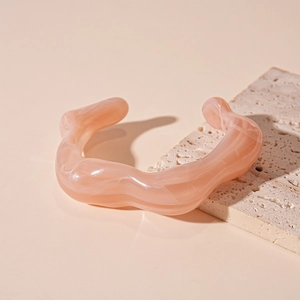 Detail of peach acrylic bangle with marble texture on natural stone display