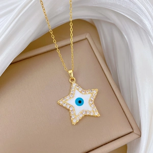 Macro shot of gold star necklace with blue evil eye and zircons on silk background