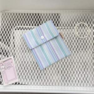 Close-up of blue and purple striped fabric sanitary napkin pouch with snap closure