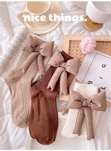 Detailed view of knitted cotton crew socks with large 3D stuffed bows in warm coffee tones