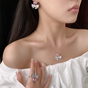 Détail du collier argenté avec pendentif coeur rose et parure de bijoux noeud assortie