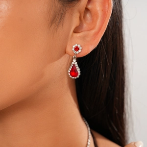 Macro shot of silver drop earrings with red gemstone and floral crystal details