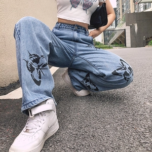 Close-up of light blue denim jeans with black butterfly print worn in a street setting