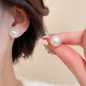 Close-up of vintage round pearl earrings with detailed golden textured metal frames