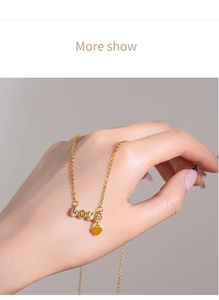 Detail of gold LOVE letter pendant with rhinestones and heart tassel on a delicate chain