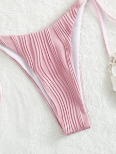 Dettaglio slip bikini rosa a pieghe che mostra la trama del tessuto e il laccio laterale
