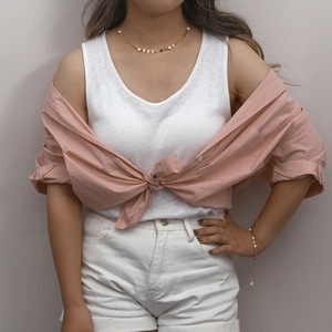 Fashionable layered gold pearl necklace and bracelet set worn with a casual pink shirt