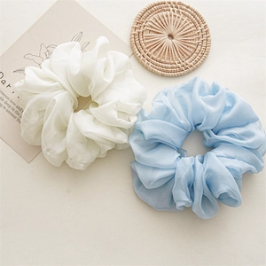 Detail view of large white and blue chiffon scrunchies on a soft beige decorative background