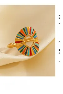 Macro view of golden fan-shaped ring featuring colorful rainbow enamel on silk background