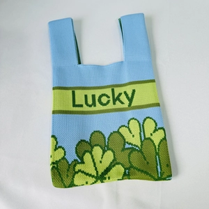 Detail view of the knitted lucky clover tote bag showing soft blue and green textures