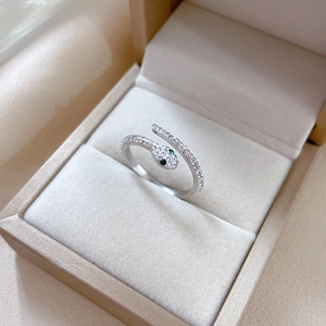 Close-up of silver snake ring with green zircon eyes and crystal pavé on velvet