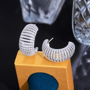 Macro shot of silver C-shaped hoop earrings with sparkling white zircons on a stand