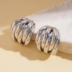 Detail of silver layered textured geometric earrings on stone display with sharp shadows