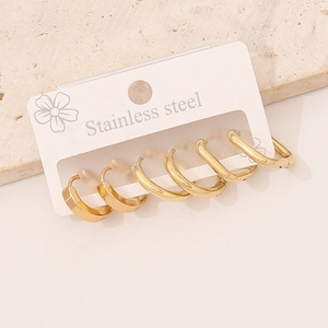 Three pairs of golden stainless steel hoop earrings in different sizes on a display card
