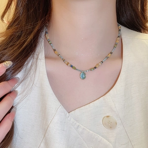 Close-up of vintage beaded necklace with blue oval opal pendant on model neck