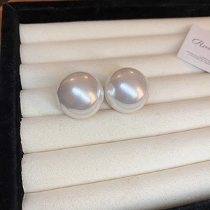 Macro shot of elegant white round pearl earrings on a soft cream jewelry display