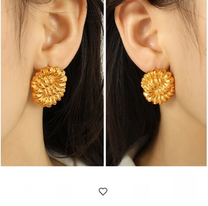Detailed view of large gold titanium steel hoop earrings with sunflower spiral texture