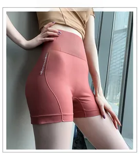 Détail du short de yoga taille haute rose avec lettrage latéral blanc et coupe galbante