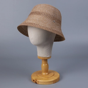 Elegant brown woven sun hat for women with a silver flower accent on a display stand